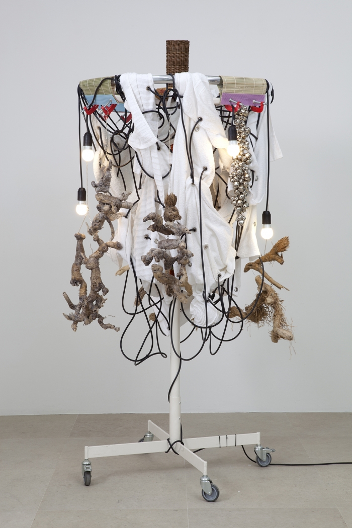 Haegue Yang Towel Light Sculpture - Organic Hygienic, 2012 Single shaft clothing rack (white) on casters with round top, light bulbs (frosted), cable, towel (white, used and new), knitting yarn, bells, wicker hamster tunnel, bamboo sushi matt, dog training dummy, wooden pet ball with bell, bamboo roots, wicker pet ring, chain, grommets, and glue press 79 1/8 x 45 x 45 inches 201 x 114.3 x 114.3 cm