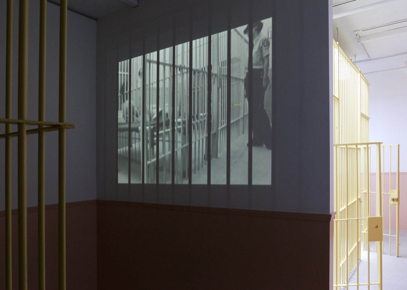 Tony Conrad WiP, 2013 Mixed media installation with wooden bars, locks, bunk beds, moving blankets, bed pans, sinks, overhead LED lighting, and video Dimensions variable