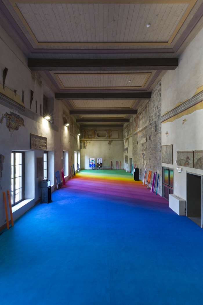 A corridor with rainbow carpeting leading to two monitors on a far wall.