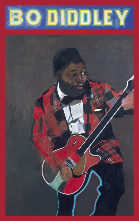 Man playing guitar wearing red plaid blazer, with "Bo Diddley" written across top of board