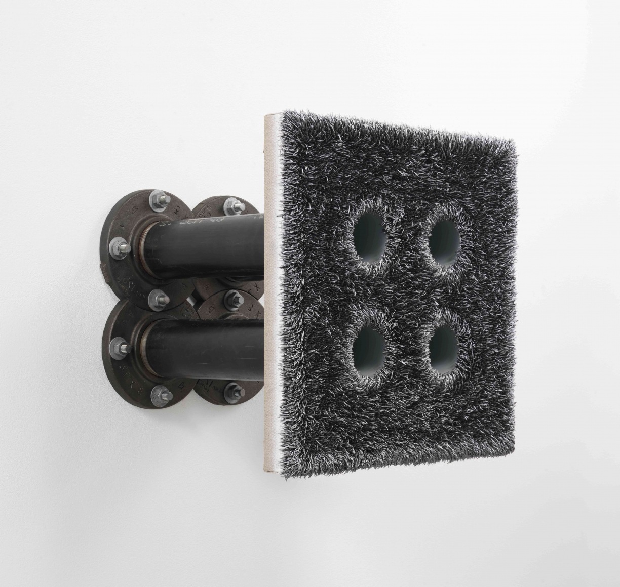 Extruded painting with four holes drilled in it attached to a wall with pipes by Donald Moffett