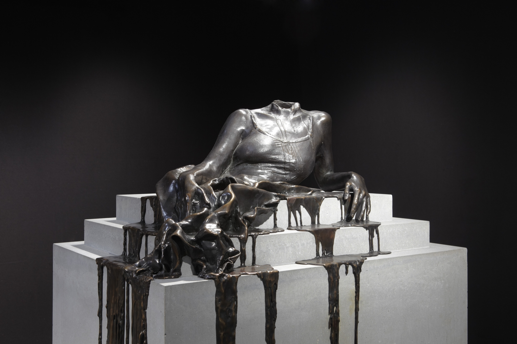a bronze sculpture of a headless woman dripping off a pedestal by Diana Al-Hadid