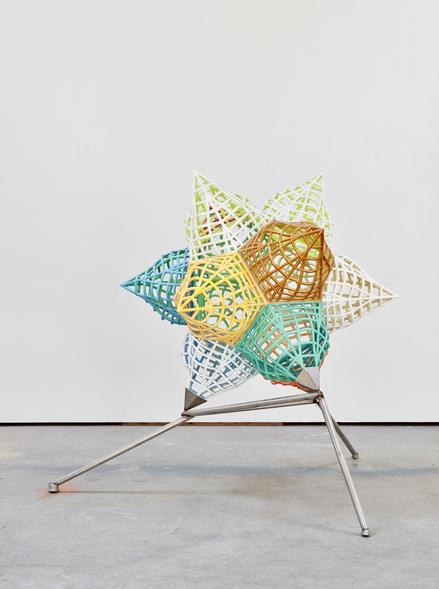 a metal 3 dimensional star in bright colors by artist frank stella and exhibited in a gallery