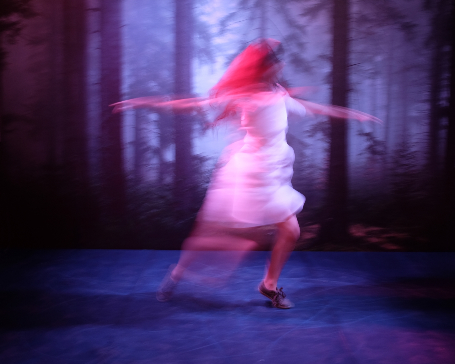 a woman spinning in a forest from a video by sue de beer in an art gallery