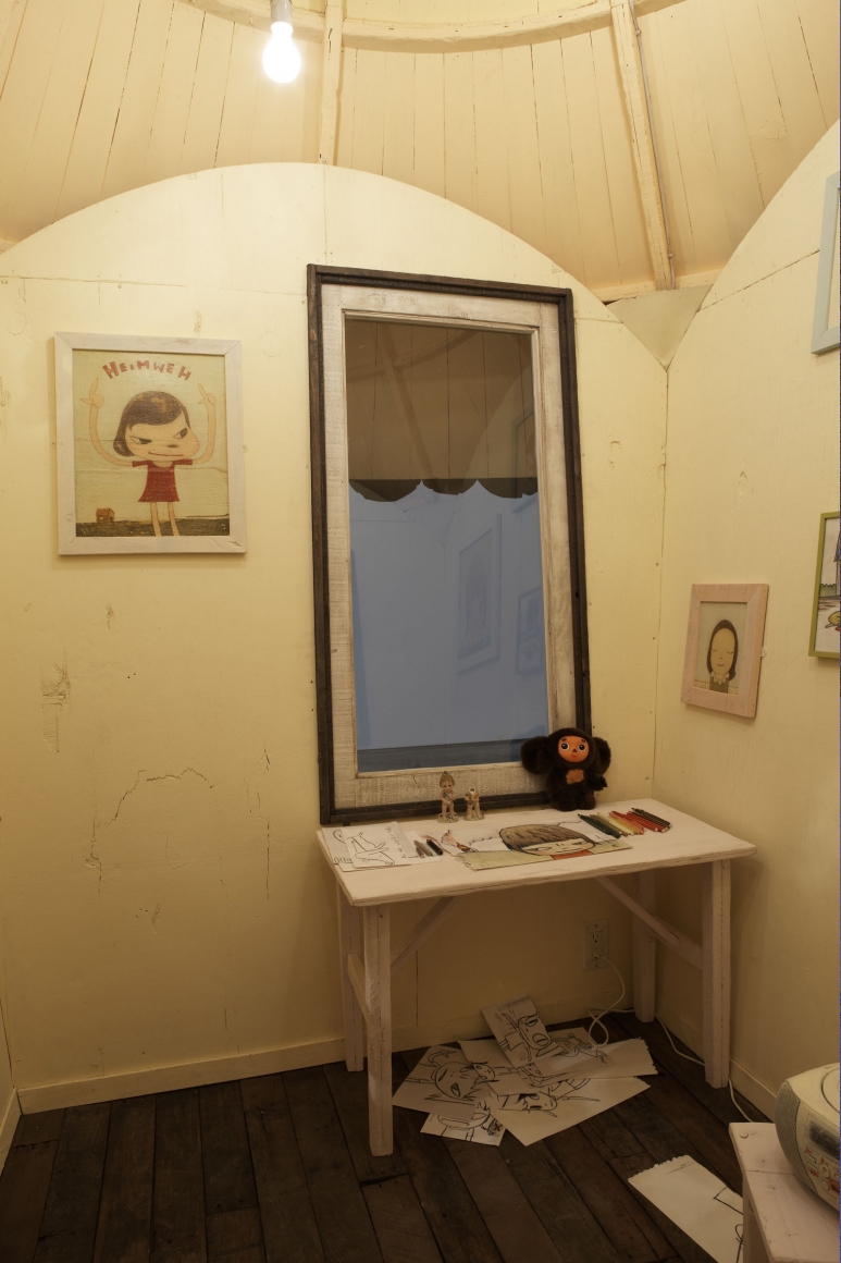 house interior with desk and drawings by yoshimoto nara