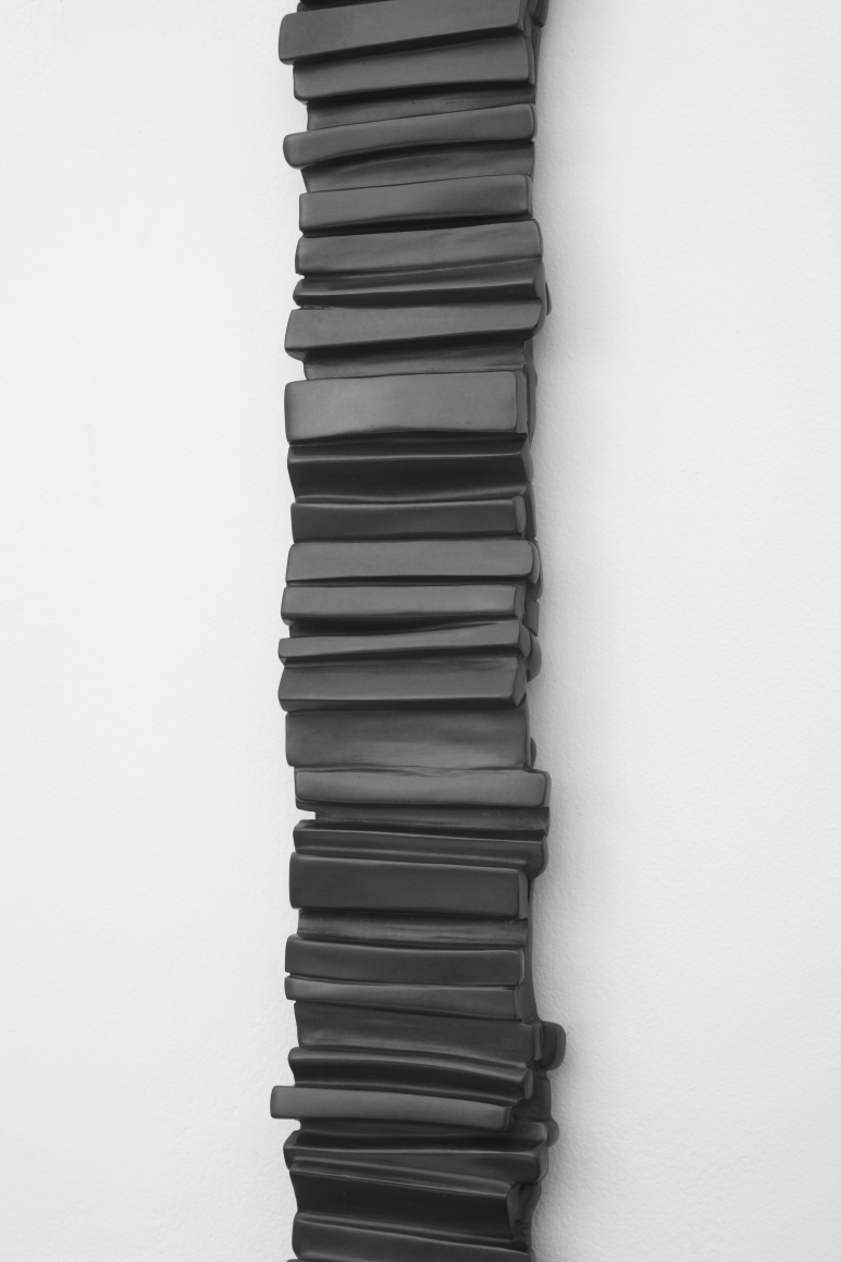 a detail of a vertical bronze wall hanging by anthony pearson composed of small stripes