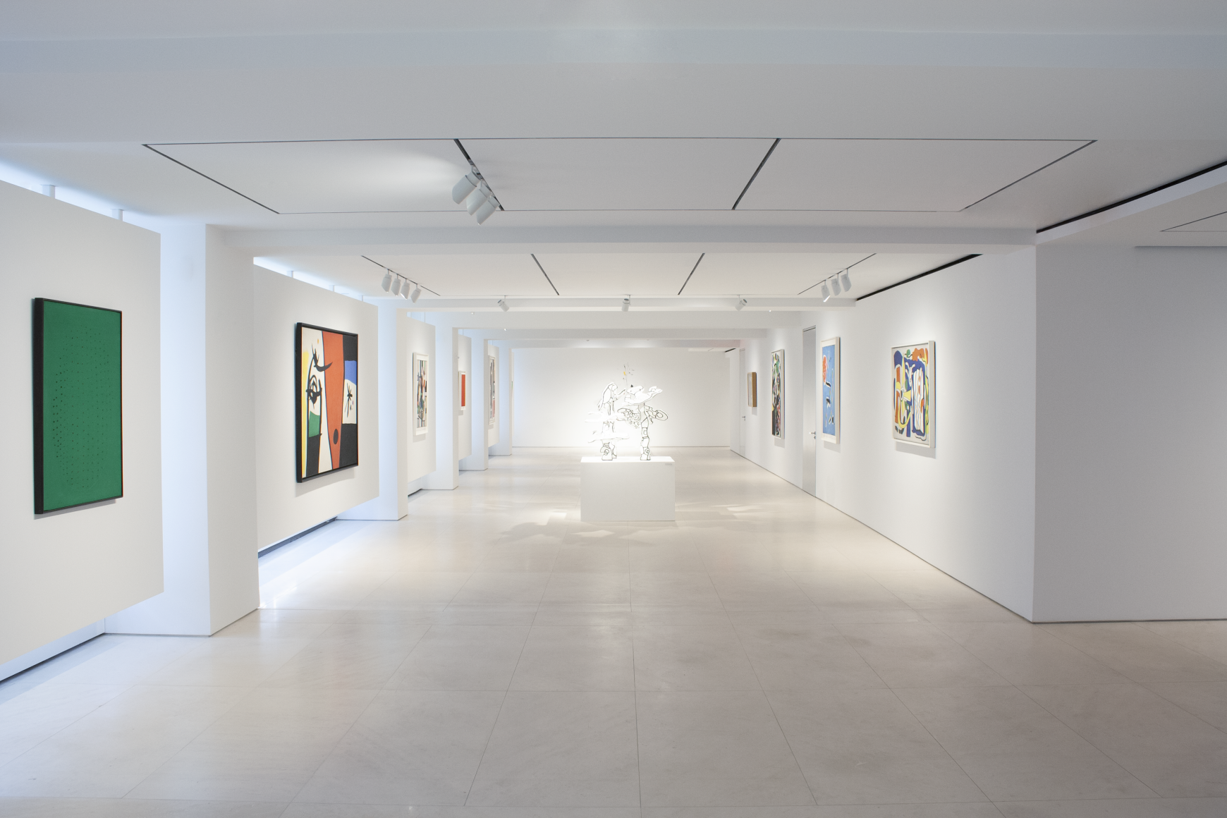 This is a general view of the main gallery on the second floor, which features from afar five paintings on the left wall and four painting on the right wall. There is a sculpture by Jean Dubuffet featured in the center of the gallery.