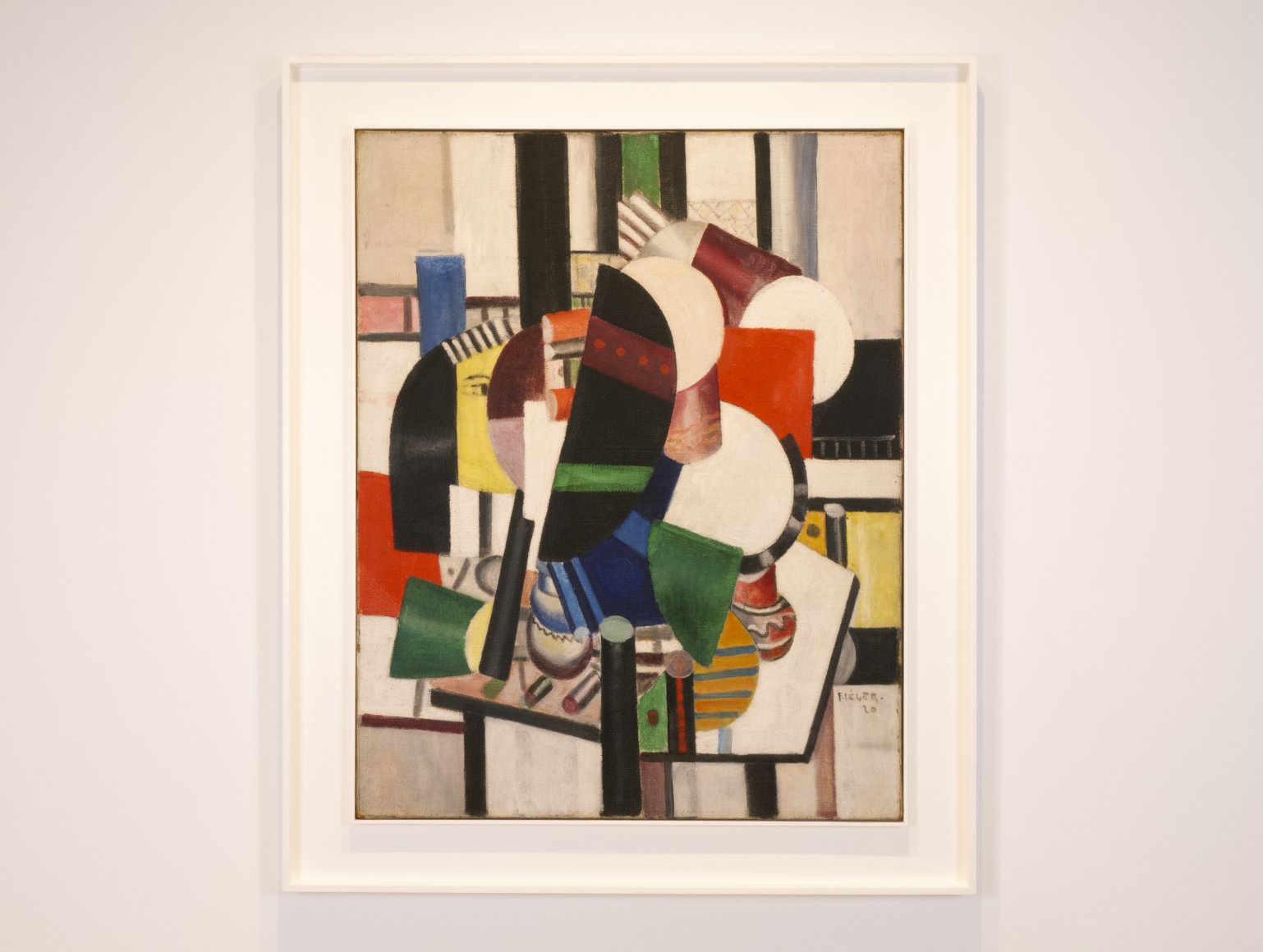 This is a photo od a painting by fernand Leger, which is titled "FLes Femmes à la Toilette" and was produced in 1920. It is pretty abstract, geometrical forms are depicted in a rich pastel palette of pink, blue, beige, grey and black. We can identify a table at the center where all these geometrical forms are accumulated, we can also see two lipsticks on that table. We can perceive ta bit of a woman's face from profile with dark straight hair.
