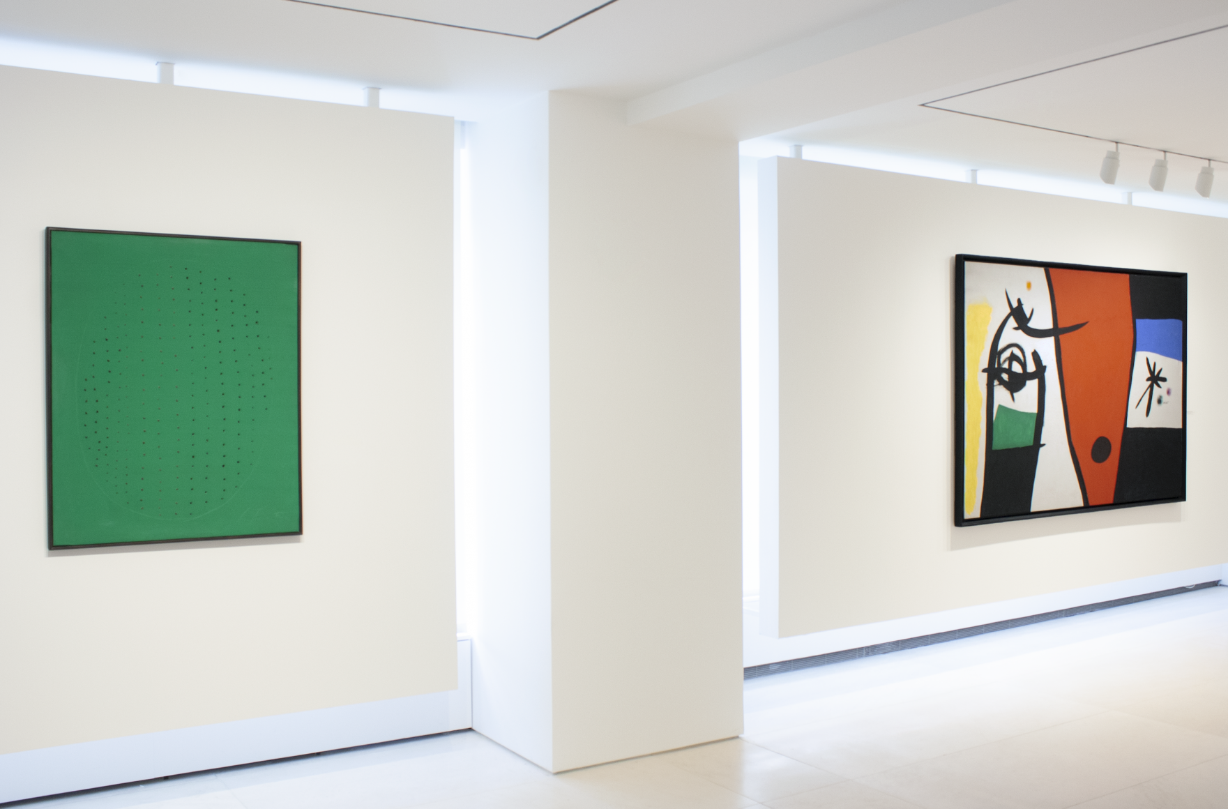 This is an installation view which features a green painting by Lucio Fontana and a large scale painting by Joan Miro.