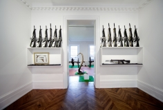 "Décor: A Conquest" (XXth Century Room), 1975, One light reflector (with red light), one small green parasol, garden table with one striped blue parasol displaying one jigsaw puzzle with box, four white garden chairs with matching cushions, one AR 15 Rifle, one hand grenade revolver Smith and Wesson Mod. 36 (in vitrine), five AR 15, three FN Rifles M16, a framed print of German Luger, fourteen assorted pistols (one colt Frontier, Beretta, Colt official Police, Snub Magnum, Chief Special, Walther P 38, two Chief Specials, one Tokarev T 33 / Luger, five AR15, two FN rifles (in vitrine).