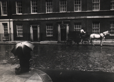 David Newell Smith, The man in Downing Street was praying for Mr. Wilson who had just become the Prime Minister, c. 1966. A figure with an umbrella kneels on the lower left of the frame across the street from a horse-drawn carriage.