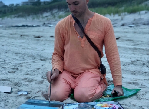 image of a man painting on a beach