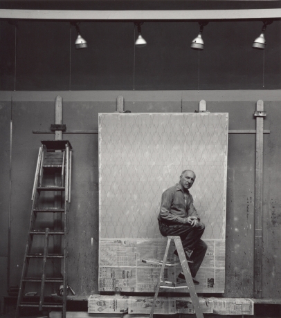 image of a man sitting on a ladder with a painting in progress in the background