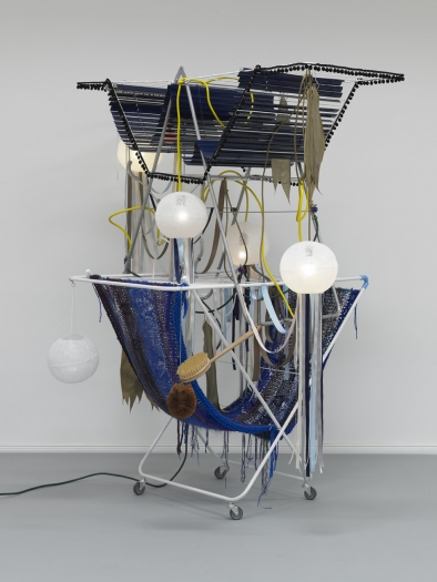 Haegue Yang Dilemma Circus, 2010 2 drying racks on casters, light bulbs (frosted), lamp shades, cable, ribbon, aluminum venetian blinds, knitting yarn, dried lotus leaves, cosmetic sponge, metal ring, metal chain, body brush 57 1/8 x 49 1/4 x 72 3/4 inches (145 x 125 x 185 cm)