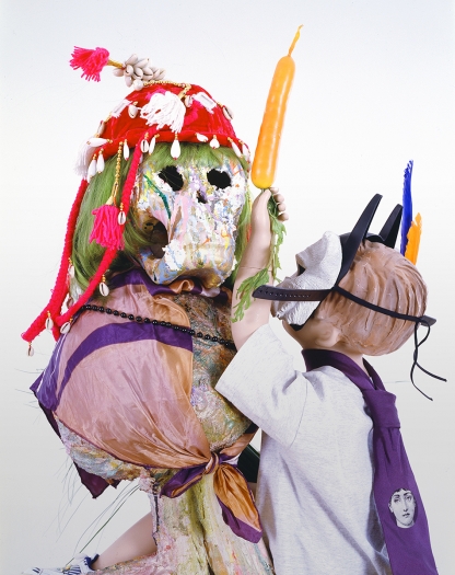 Rachel Harrison I'm with Stupid, 2007 Wood, polystyrene, cement, acrylic, child mannequin, papier-mâche skull, green wig, festive hat, Spongebob Squarepants sneakers, Pokemon t-shirt, wheels, canned fruits and vegetables, fake carrot, fake feathers, fake grass, Batman mask, cat mask, necktie, scarf, and plastic beads 65 x 31 x 24 inches (165.1 x 78.7 x 61 cm)
