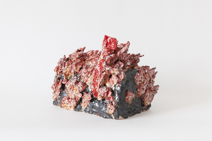 A ceramic piece with glossy black glaze covered in sharp, jagged red shapes depicting flames.
