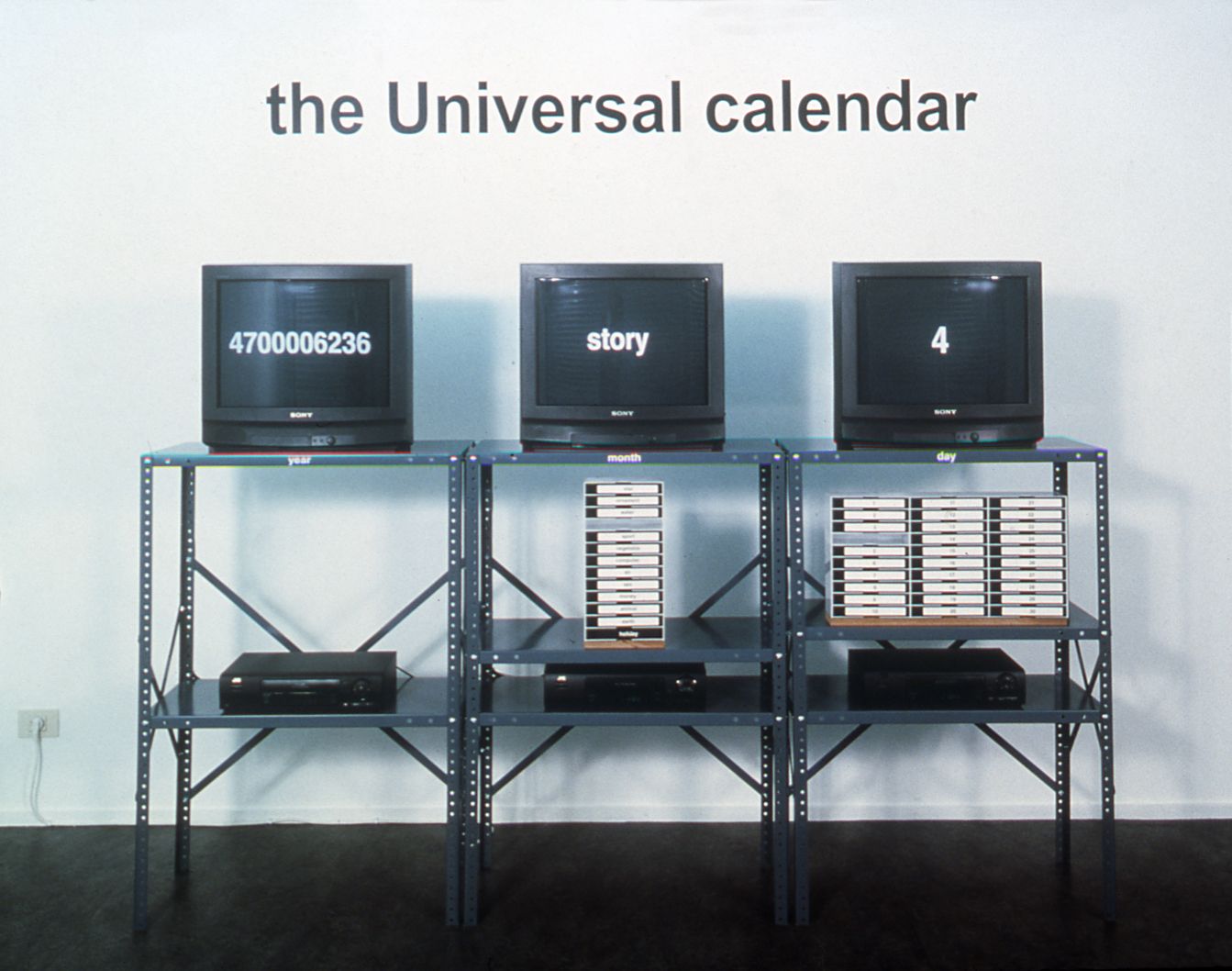 Jonathan Horowitz, The Universal Calendar, 1999, 43 continuous vhs tapes, industrial stand, wall text