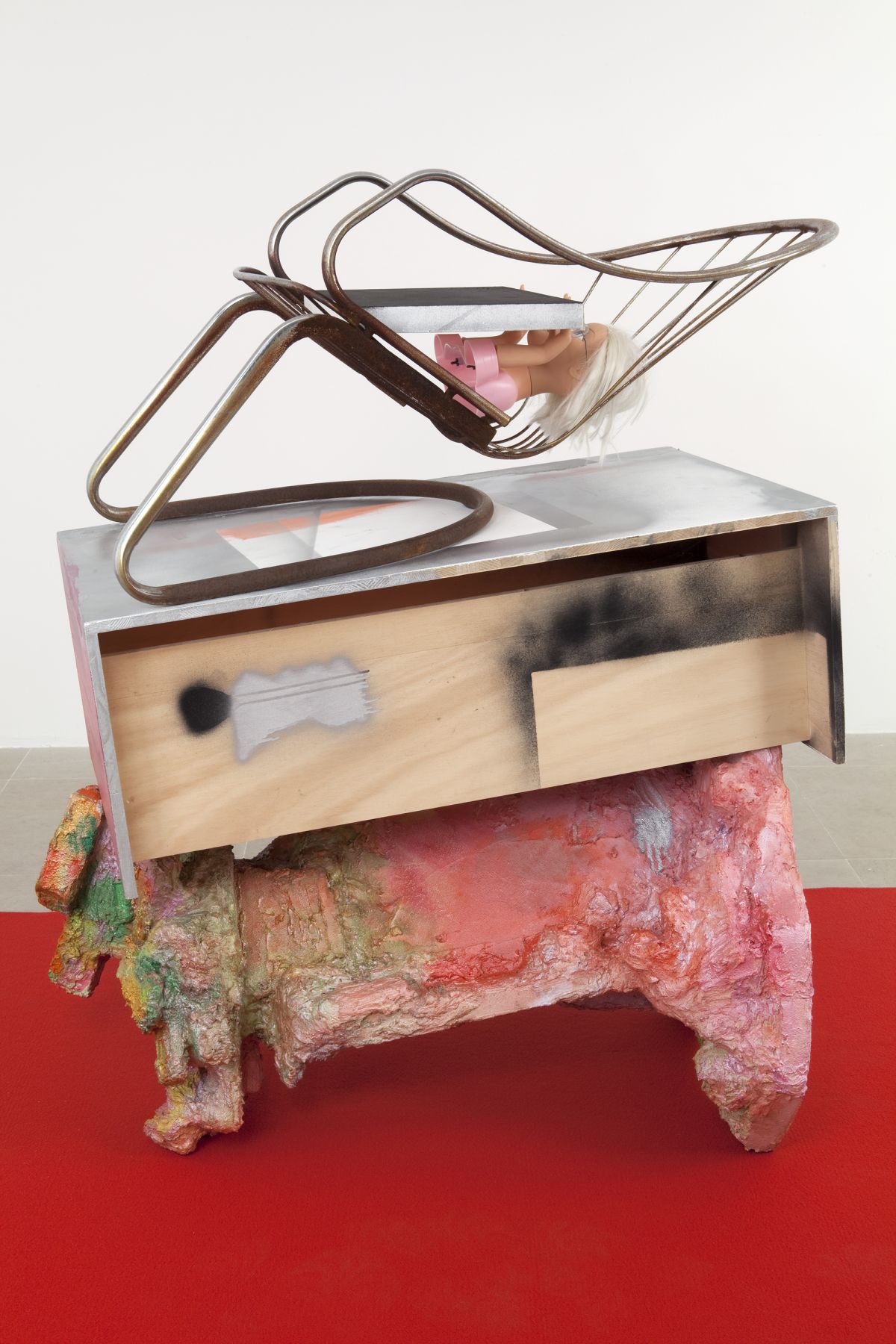 Rachel Harrison, The Spoon Bender, 2011, wood, polystyrene, cement, acrylic, felt, canvas, steel chair, plastic doll, and eyeglasses, 53 1/2 x 59 x 77 inches overall