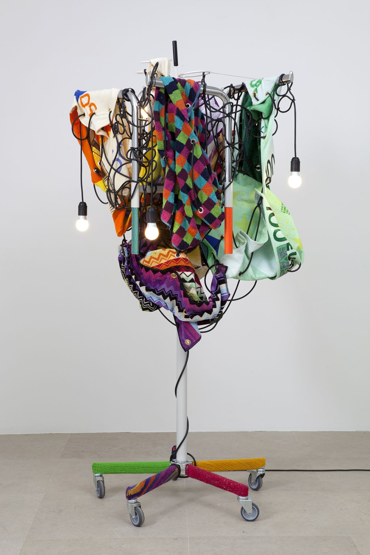 Haegue Yang Towel Light Sculpture - Budget Discipline towards 900 Euro, 2012 Single shaft clothing rack (white, chrome) on casters with 4 arms, light bulbs (frosted), cable, cord, printed towel (Euro and geometric patterns), metal chain, knitting yarn, grommets, umbrella stand 75 5/8 x 34 5/8 x 33 1/2 inches 192 x 88 x 85 cm