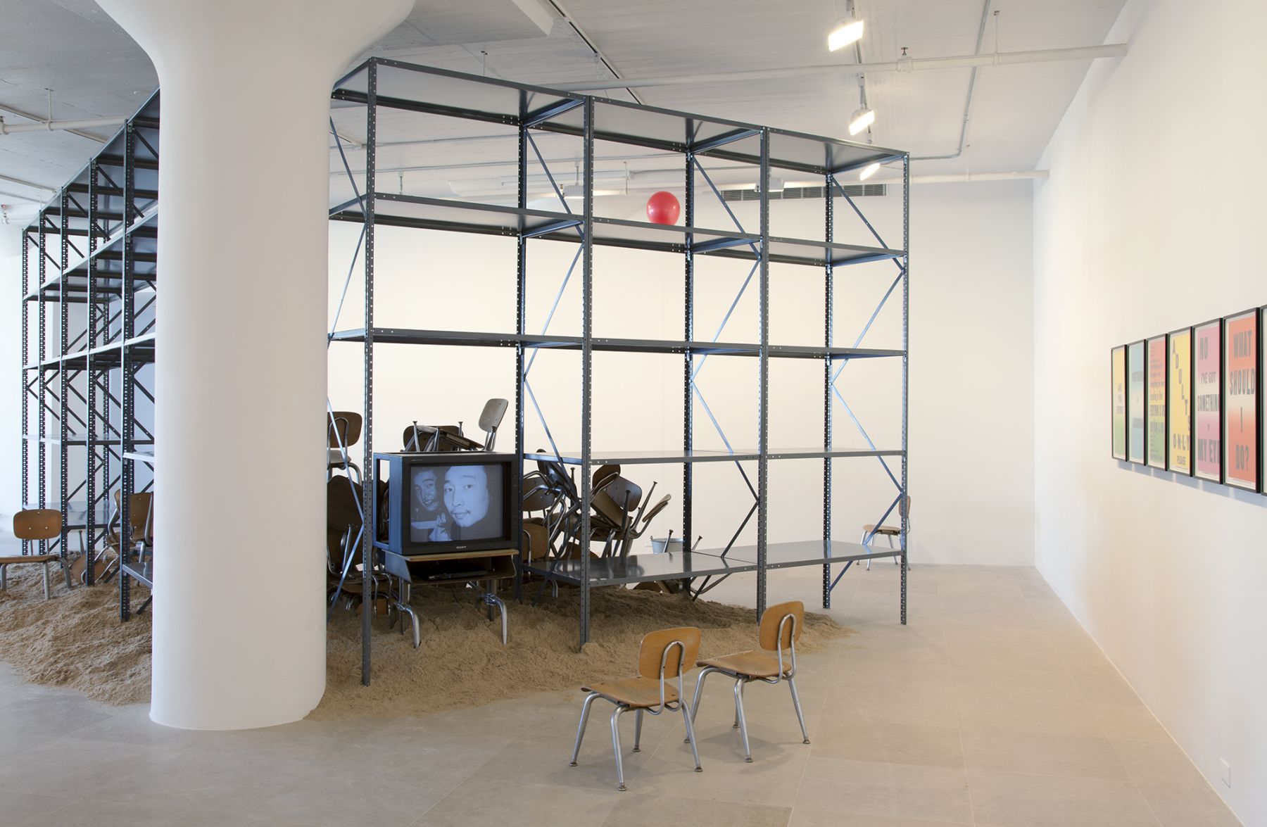 Haim Steinbach, Mothers, Daughters, Children (with ’37 Stories About Leaving Home’ by Shelly Silver), 1997-2011, metal shelving, sand, wood and metal tables, wood and metal chairs, LCD TV, galvanized bucket, and latex ballon, installation dimensions variable, Installation view, Greene Naftali, New York, 2012