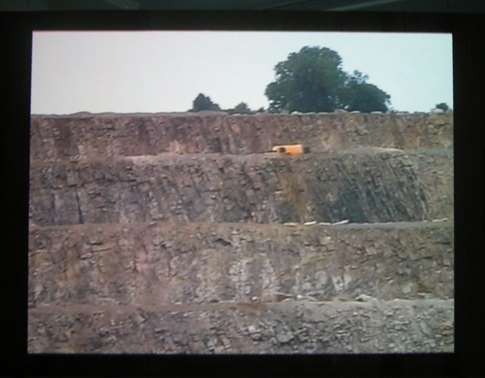 Quarry, 2003 (still), Two Parts: “Blast” (4 minutes), “Dr. Chris Alabaster” (12 minutes), 2 DVDs, bleachers, wooden screen, Installation dimensions variable