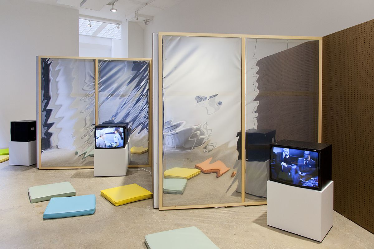 Dan Graham TV Producer as Conceptual Artist, 2018 Perforated Masonite, Mylar, pine armature, vinyl-upholstered cushions, 5 CRT monitors, pedestals, media players, headphones Dimensions variable
