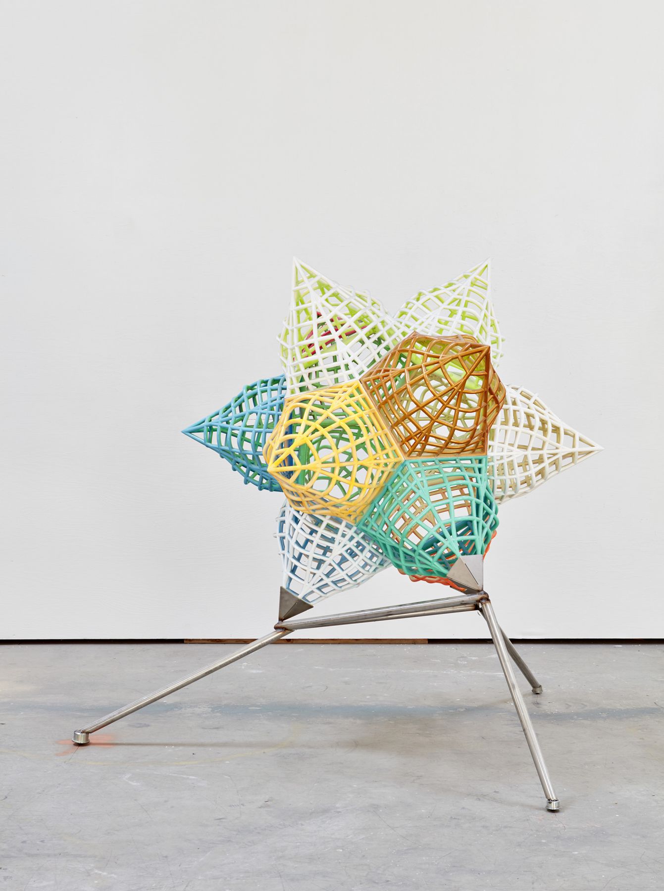 a metal 3 dimensional star in bright colors by artist frank stella and exhibited in a gallery