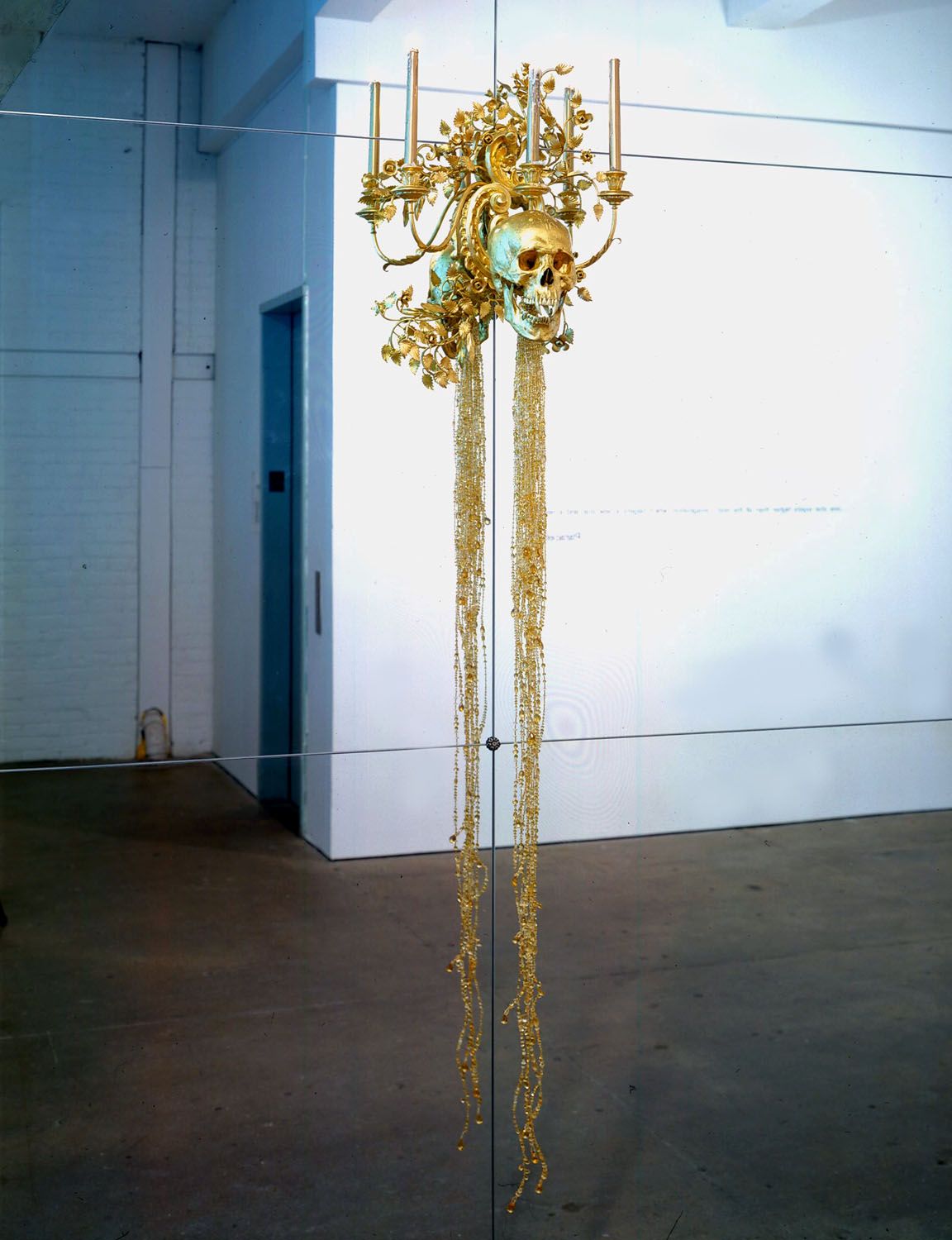 gold skull mounted on a mirror by angelo filomeno