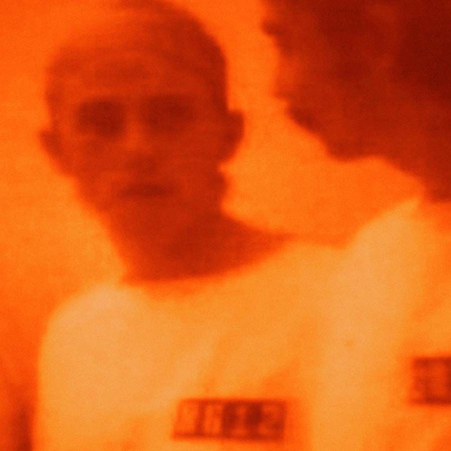 orange photograph of a man looking at himself in the mirror by kon trubkovich
