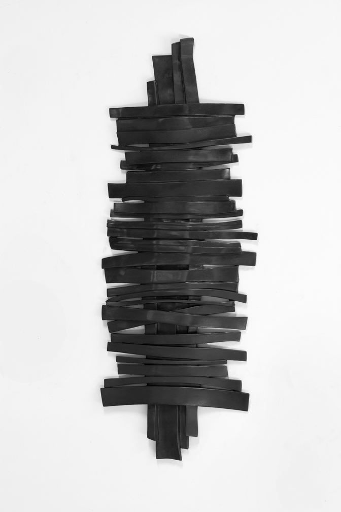 a bronze wall sculpture of horizontal strips overlaying a vertical strip by anthony pearson