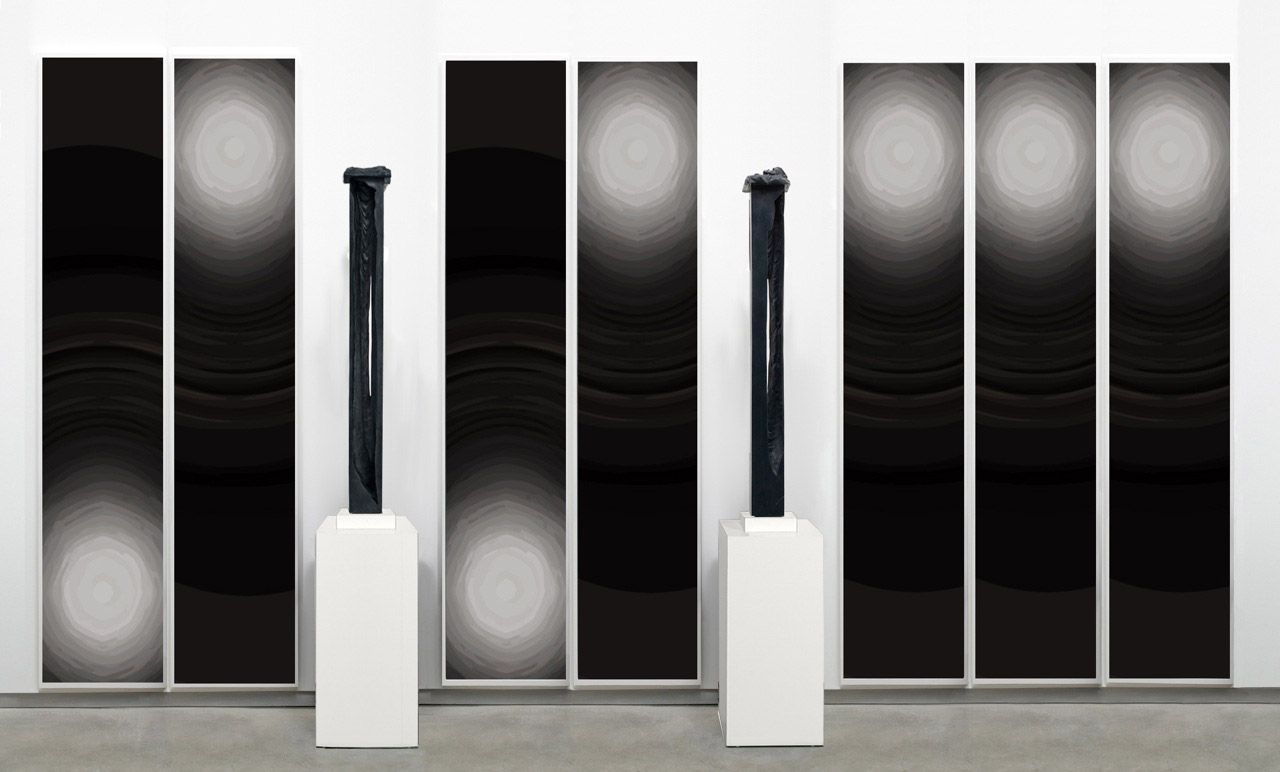 arrangement by anthony pearson with two black rectangular sculptures and six paintings
