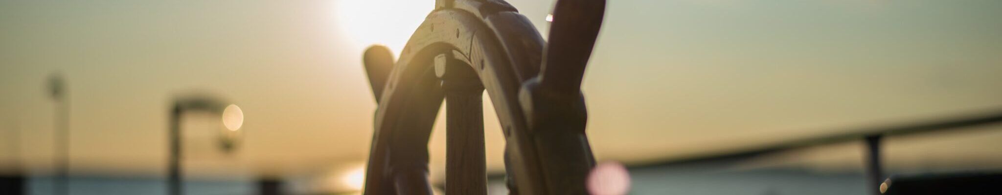 The steering wheel of a ship shines in the sunlight