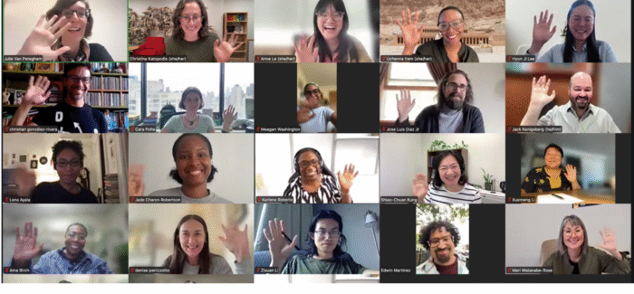 A large group of people smiling and waving on zoom