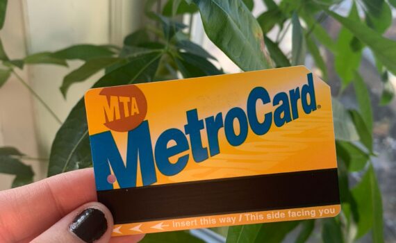 image of a hand with naipolish hoding a MTA metro card with plant in the background