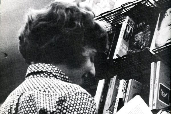 Student looking at a book under a sign that has the word Criticism on it.