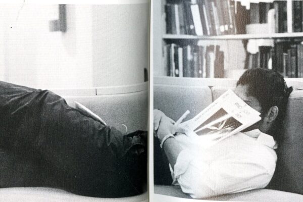 Student sleeping on couch in library with book covering their face.