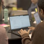 students working on laptop at table