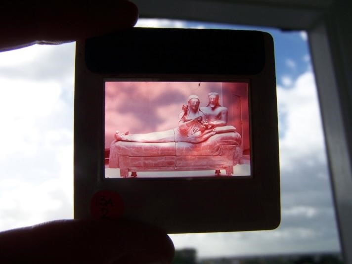 An image of an Ektachrome slide held to the light showing the fading down to only the magenta layer that is typical of that medium over time
