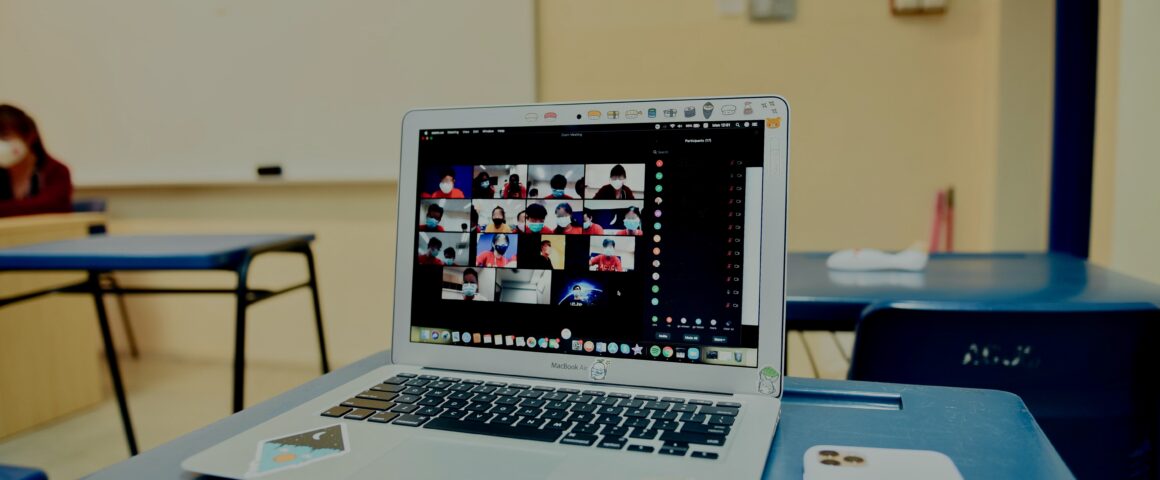 A laptop in an empty classroom displays Zoom classroom on its screen.