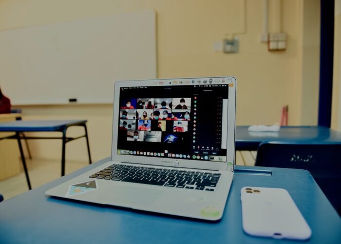 A laptop in an empty classroom displays Zoom classroom on its screen.