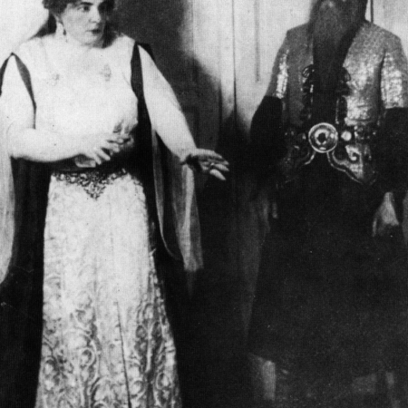 Bartók_-_Bluebeards's_Castle_-_Olga_Haselbeck_and_Oszkár_Kálmán_in_the_first_performance_1918 Photo of a man on the right with a beard staring intently to the woman on the left who wears a white robe and a triangular hat