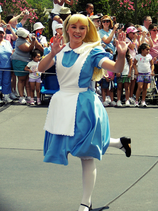 women in blue dress and white apron skipping
