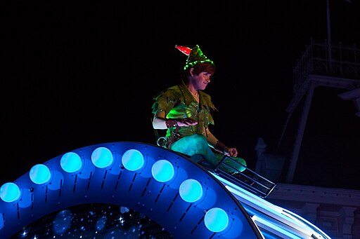 Night time photo of Disney's Peter Pan, lit in green, sitting atop a blue lit float
