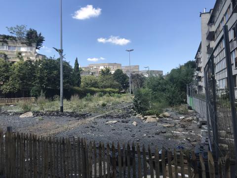 An abandoned lot in Paris, fences in but with greenery growing along the edges.