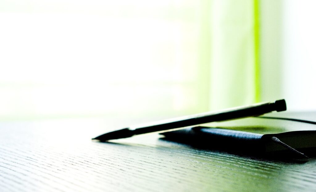 Mechanical pencil rests on a folder against a background of abstract green light 