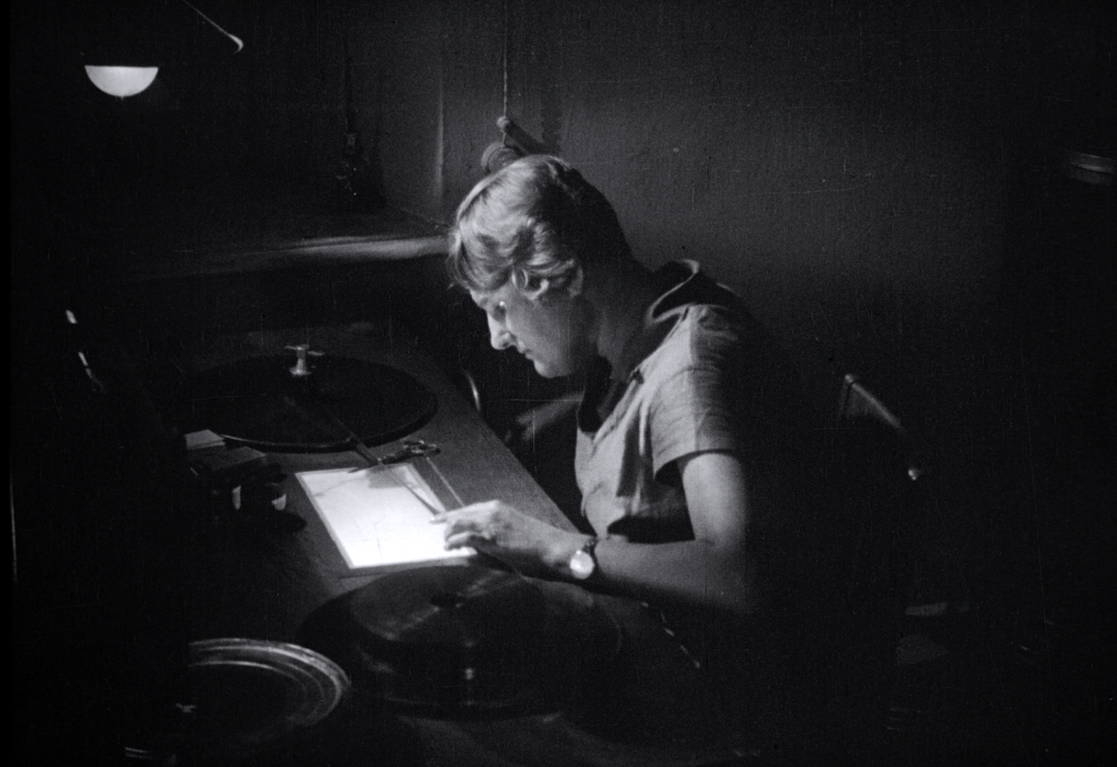 Elizaveta Svilova at her editing desk. She is looking at a strip of film