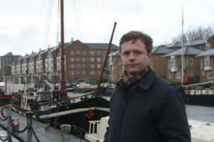 Johnathan Thayer in front of a boat docked on the water