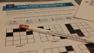 Figure 1. snapshot of graph-paper programming by Twitter user Sheena1010. Pencil resting on activity sheet, showing patterns of filled-in and blank squares on graph paper.