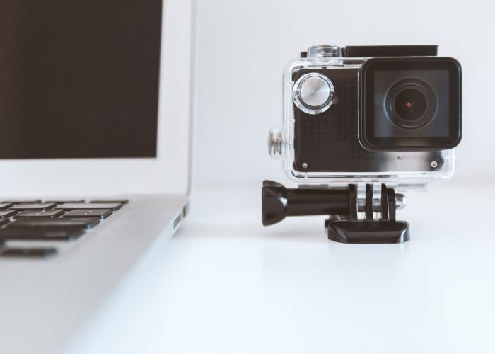 A digital camera stands next to a laptop computer.