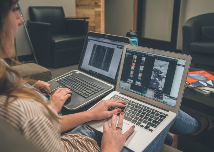 A woman works at a laptop looking at an image of a snowy landscape.